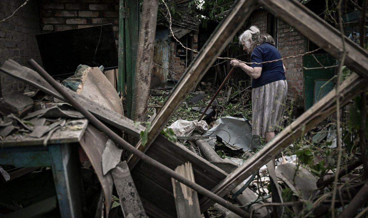 Пожилая женщина у разрушенного дома