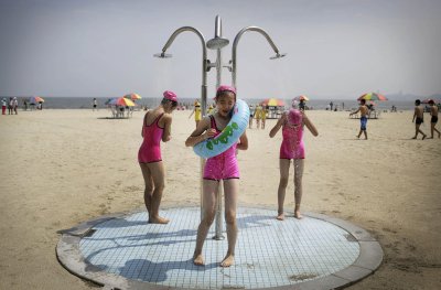 Põhja-Korea tüdrukud ühesugustes ujumistrikoodes rahvusvahelise lastelaagri rannas dušši võtmas.