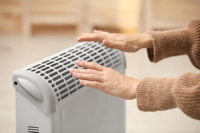 Woman,Warming,Hands,On,Electric,Heater,At,Home,,Closeup