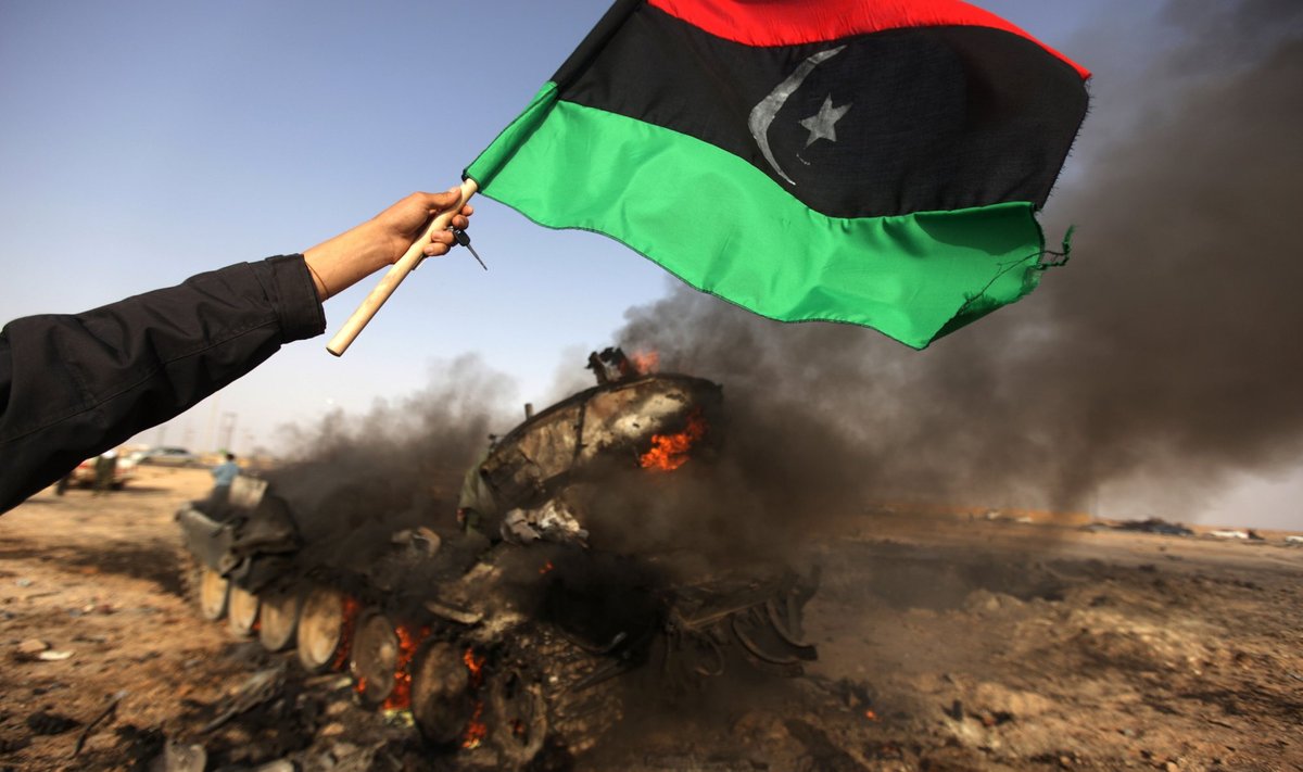 Mässuline hoiab Liibüa lippu põleva tanki kohal 2011. aasta araabia kevade ajal