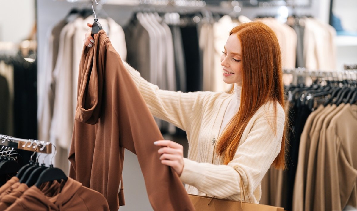 Side,View,Of,Cheerful,Pretty,Young,Woman,Buyer,Choosing,Clothes