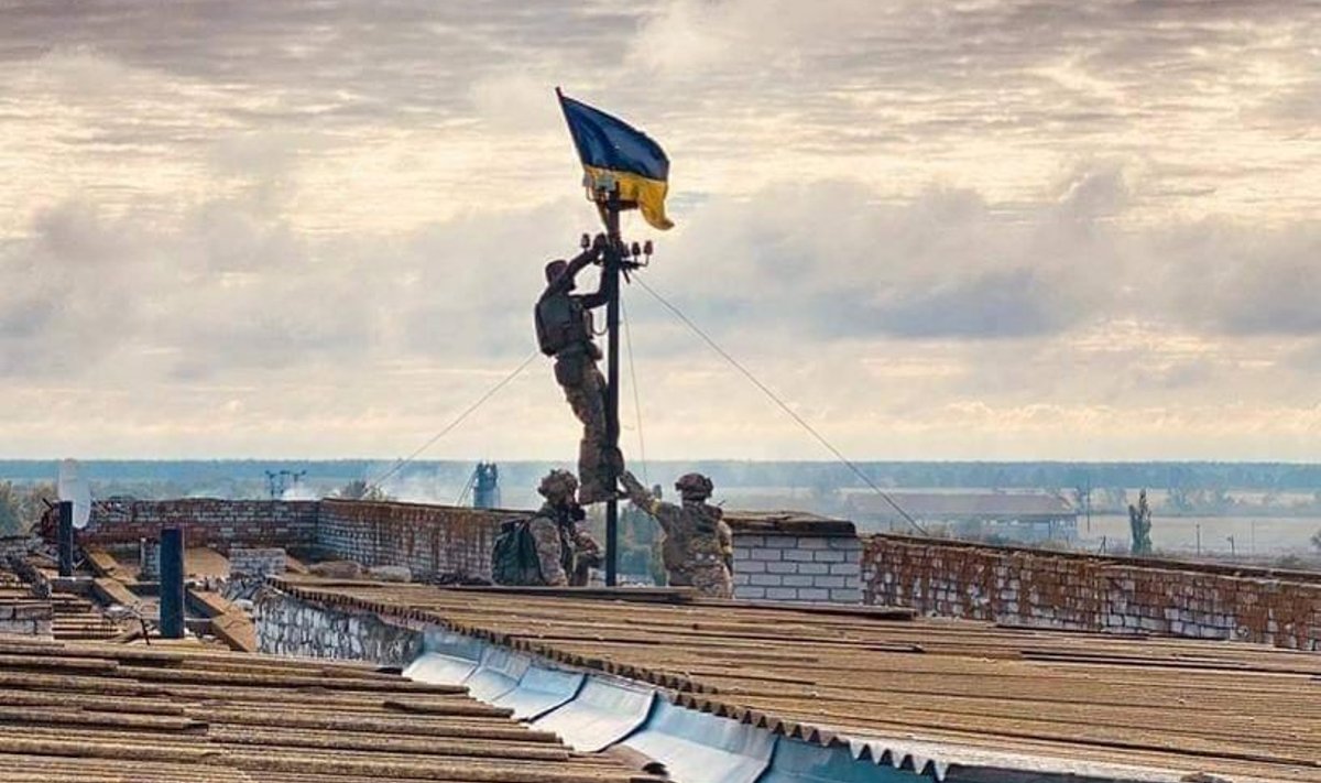 Украинский военный поднимает флаг над зданием в Высокополье