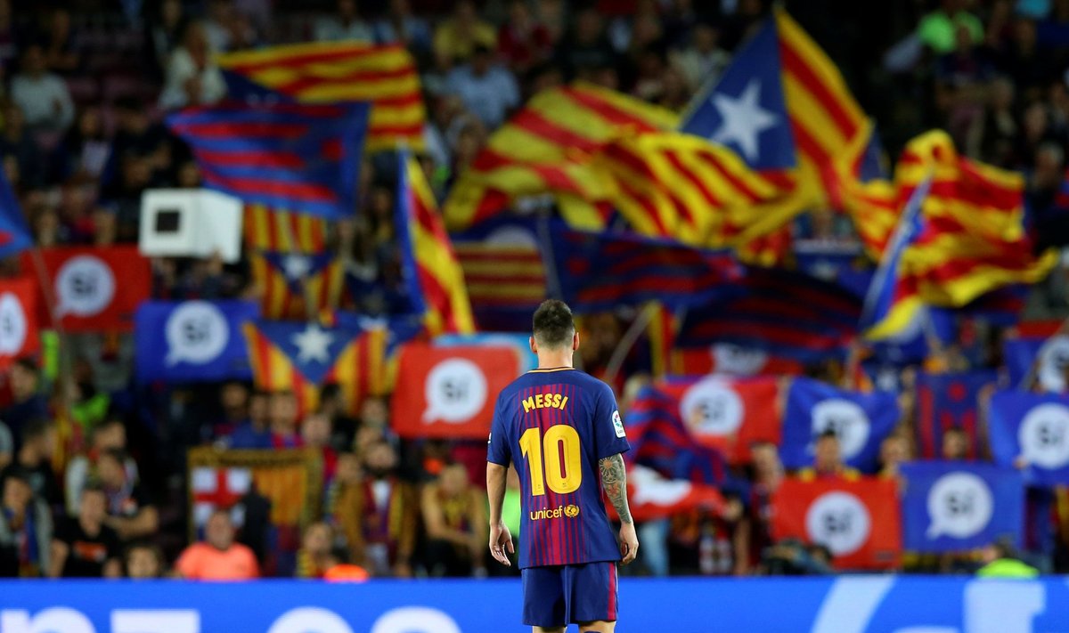 Barcelona's Lionel Messi stands on the pitch in the Camp Nou stadium as fans wave pro-independence flags and banners during a Spanish La Liga match against Eibar in Barcelona