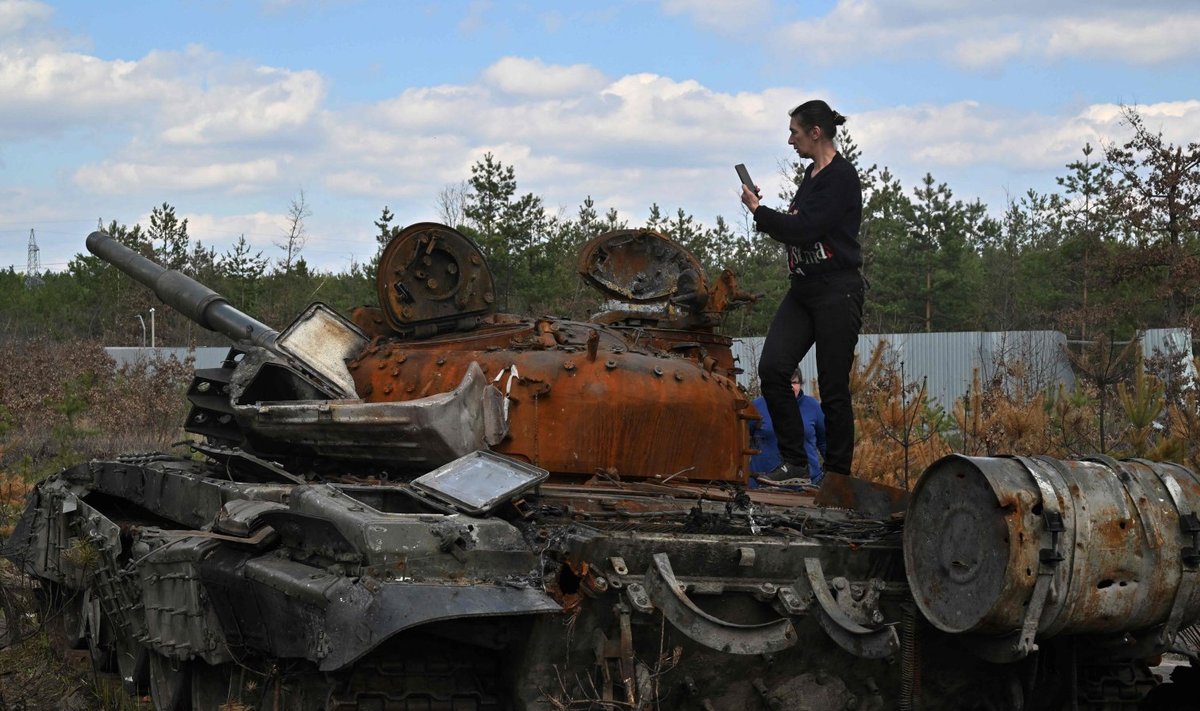 Ukrainlanna tegemas fotot purustatud vene tankil seistes. Foto tehtud Dmytrivka külas Kiievi oblastis 24. aprillil 2022 
