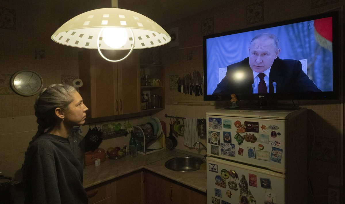 Женщина смотрит выступление Владимира Путина по телевизору