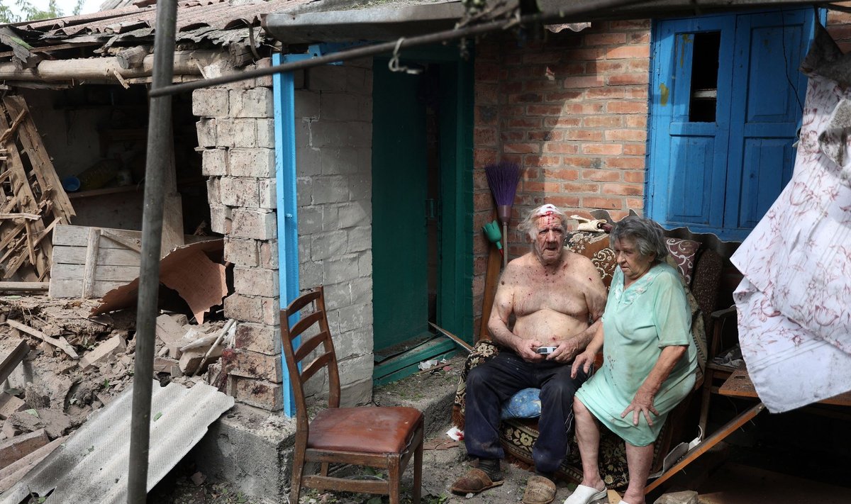 Раненый мужчина и его жена сидят во дворе своего сильно поврежденного дома после ракетного обстрела города Бахмут (Донецкая область, 12 августа 2022 года).